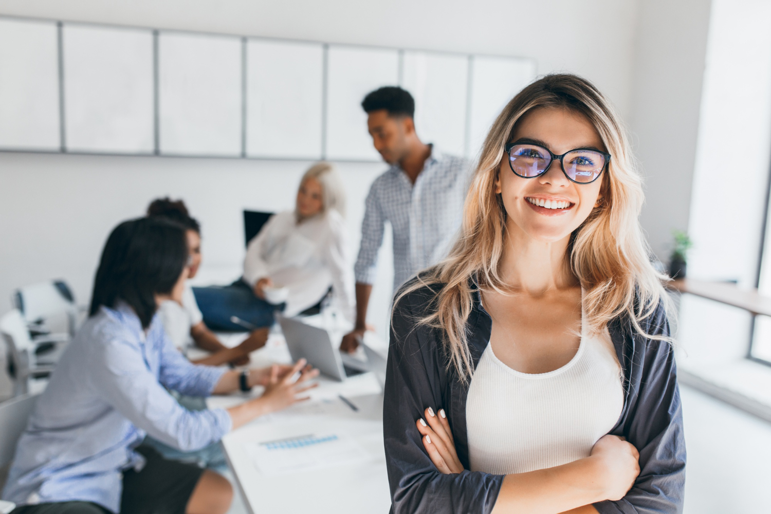 Woman smiling whilst her team work around a table in the background