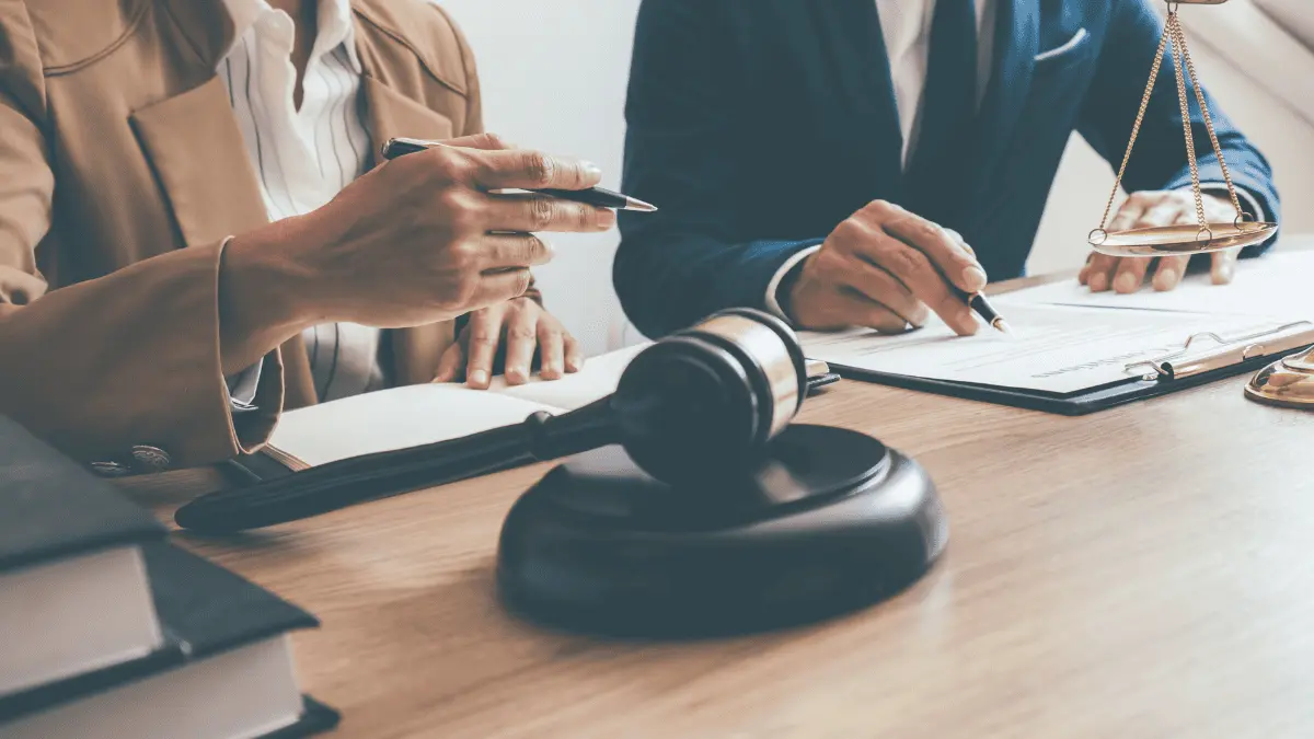 A man and woman sat at a desk with a gavel and documents for Joint and Several Liability